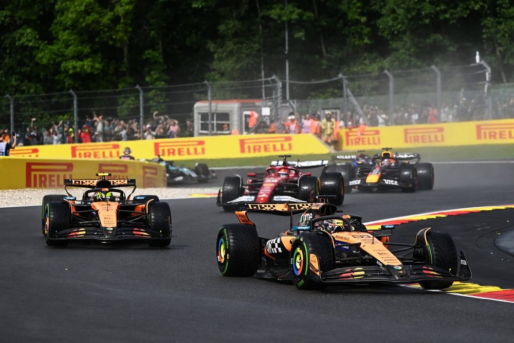 Monoplazas girando en la primera vuelta del GP de Bélgica 2025 bajo lluvia intensa en Spa.