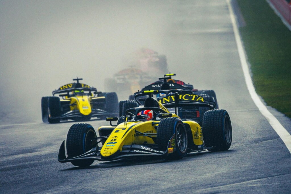 Monoplazas de F2 con Stanek y Brownie liderando en pista mojada, mientras Fornaroli sigue detrás durante la carrera bajo lluvia intensa en Spa 2025.