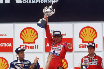 Ayrton Senna celebra exhausto en el podio del Gran Premio de Brasil 1991 en Interlagos, sosteniendo el trofeo y haciendo delirar a todo Brasil.
